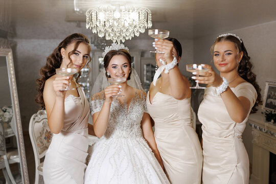 A group of women are celebrating a wedding, and they are all holding up their wine glasses. The bride is in the center of the group, and the other women are standing around her