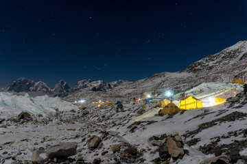 Night time sky over Everest base camp on Khumbu glacier. Tents are lit with lights from inside....