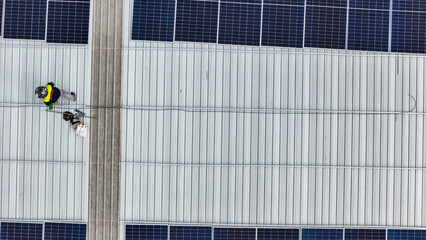 Aerial view of a rooftop with solar panels, showing a technician in safety gear performing maintenance. The scene highlights renewable energy, solar technology, and sustainable infrastructure.