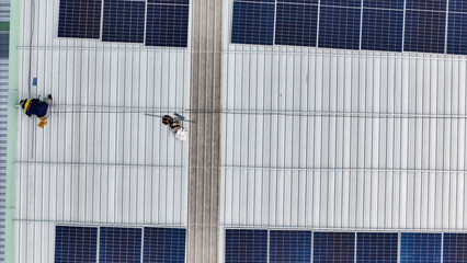 Aerial view of a rooftop with solar panels, showing a technician in safety gear performing maintenance. The scene highlights renewable energy, solar technology, and sustainable infrastructure.