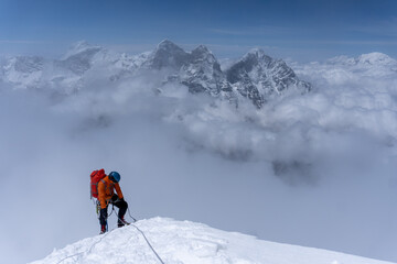 Man wearing a orange jacket, summitting Ama Dablam, feeling tired. Khumbu region, Nepal.