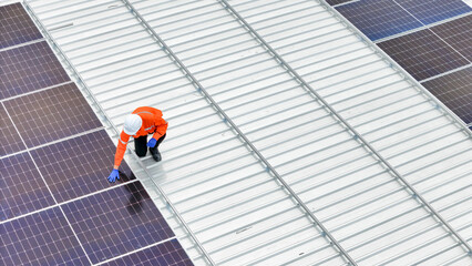 Aerial view of a rooftop with solar panels, showing a technician in safety gear performing maintenance. The scene highlights renewable energy, solar technology, and sustainable infrastructure.