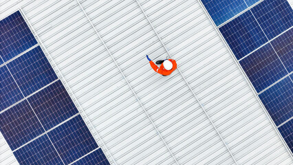 Aerial view of a rooftop with solar panels, showing a technician in safety gear performing...