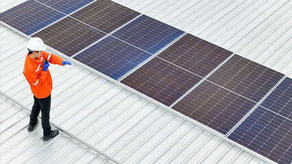 Aerial view of a rooftop with solar panels, showing a technician in safety gear performing...