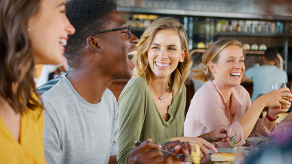 Group Of Young Friends Meeting For Drinks And Food In Restaurant Or Bar