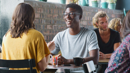 Young Couple Meeting Sitting At Table In Coffee Shop And Talking