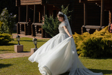 A woman in a white dress is walking in a garden. She is wearing a tiara and a veil