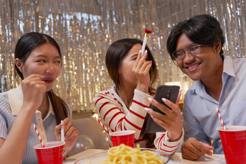 Happy friends with tasty cake and glasses of sparkling wine celebrating birthday indoors

