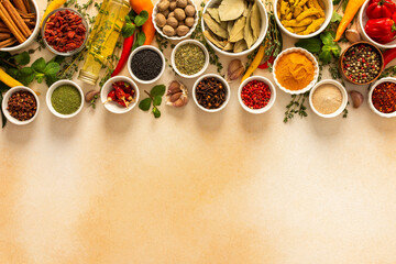 Assortment of vibrant spices and herbs on a warm beige background, showcasing a natural and aromatic palette for culinary inspiration, top view and copy space