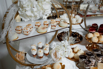 A table full of desserts, including cakes and cupcakes, with a white tablecloth and a gold tray