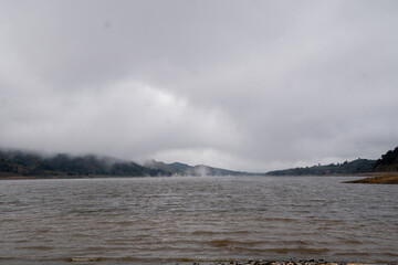 A lake surrounded by a pine forest covered by morning fog, Corani bolivia
