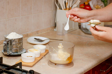 woman in kitchen adding salt and other ingredients to blender for kneading dough
