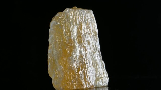 Yellow / Orange Calcite sample rotating against a black background.	