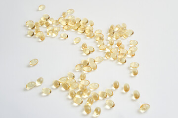 Scattered transparent omega-3 fish oil capsules on white background.