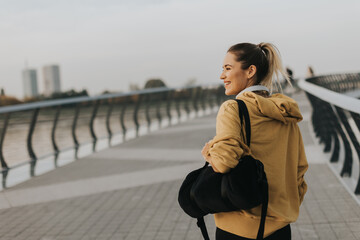 A young woman in a bright yellow hoodie enjoys an evening stroll along a picturesque riverside...