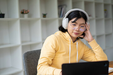 Intelligent young woman having online lessons on laptop, drinking coffee and taking notes,