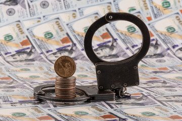 Handcuffs and American coins against the background of US $100 bills
