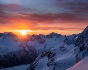 A breathtaking sunset over snowy mountains, with warm orange and pink colors in the sky, softly illuminating the icy landscape, ai.