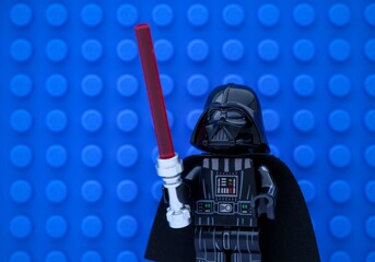 Obraz premium Tambov, Russian Federation - November 14, 2024 Portrait of Lego Darth Vader minifigure with lightsaber against a blue baseplate background