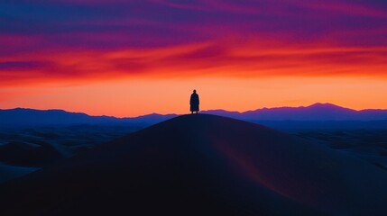 A solitary figure against a vibrant sunset in the desert