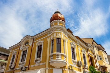 Beautiful old yellow painted building with stucco decorations in the city center of Burgas, Bulgarian Black Sea coast, partial facade view
