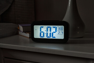 A digital alarm clock shows 602 PM in a cozy bedroom, creating an inviting atmosphere