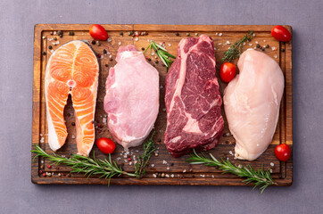 Mix of raw meat and fish . Salmon , beef , pork , chicken staek . Top view