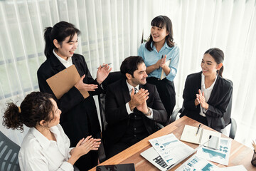 Group of happy businesspeople in celebratory gesture and successful efficient teamwork. Diverse race office worker celebrate after made progress on marketing planning in corporate office. Meticulous