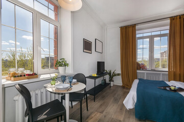 The interior of a modern studio apartment. Stylish decor. Two Windows overlooking a .landscaped courtyard on a summer day.