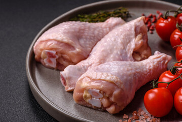 Raw chicken legs with salt, spices, herbs and tomatoes