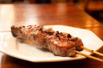 beef filet mignon skewer in close-up macro shot on plate under wooden table