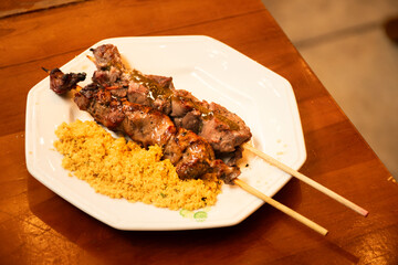 beef fillet mignon skewer with farofa in close-up macro shot on plate under wooden table