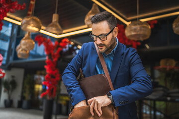Adult man put his laptop in the briefcase behind red flower background