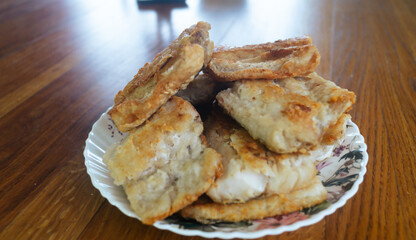 Pieces of fried fish on a plate on the table. Fried fish close-up