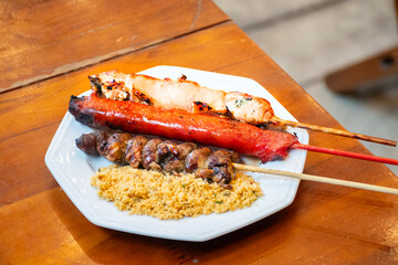 lamb skewer, chicken breast and sausage and barbecue chicken heart on a plate with farofa