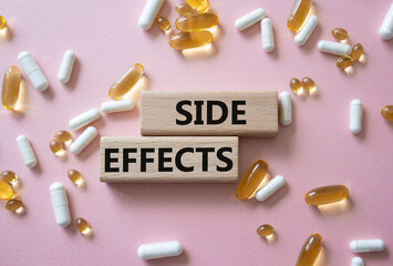 Side Effects symbol. Wooden blocks with words Side Effects. Beautiful pink background with pills. Medicine and Side Effects concept. Copy space.
