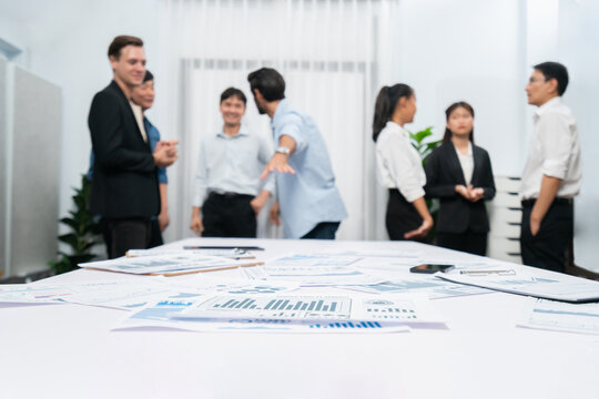 Business intelligence and analyzed financial data visualized on papers with blur background of analyst team utilizing BI Fintech in meeting room for business insight and marketing planning. Prudent