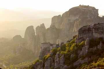 A stunning view of the Meteora monasteries in Greece, nestled on cliffs amidst green valleys and...