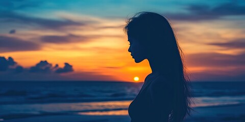 Silhouette of a female figure against a sunset backdrop by the seaside, showcasing the beauty of a tranquil evening. The female silhouette captures the essence of serenity at sunset near the sea.