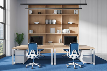 Modern office interior with wooden shelves, blue chairs, and computers on desks, large windows in background. 3D Rendering