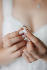 A woman is holding a ring in her hand. The ring is a diamond engagement ring. The woman is wearing...