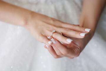 A woman is holding a ring in her hand. The ring is gold and has a diamond on it. The woman is...