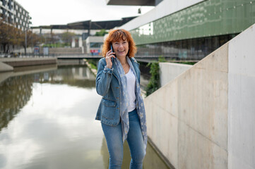 Happy businesswoman talking on smartphone while walking in the city