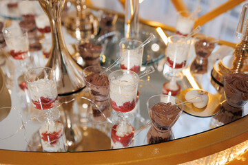 A table with a variety of desserts in small plastic cups. The desserts are arranged in a way that makes them look like they are ready to be eaten. The table is set up for a party or gathering