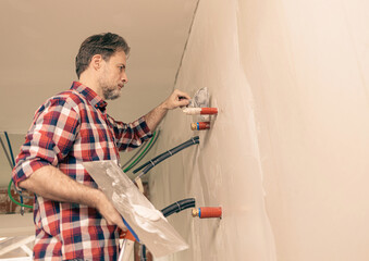 Home renovation - handyman (contractor) plasters gypsum boards walls (plasterboards, drywalls). Interior finishing works.