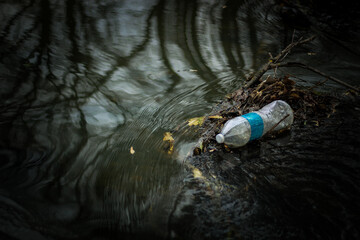 plastic watet bottle floating in creek addressing environment and pollution theme