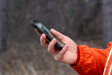 person with a phone in the hand and nature blur background