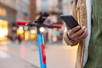 Tourist using smartphone application for electric scooter sharing in city center