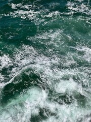 Aerial View of Turbulent Ocean Water in Rich Emerald Green and Blue Tones, capturing the dynamic movement of the sea in vibrant colors.