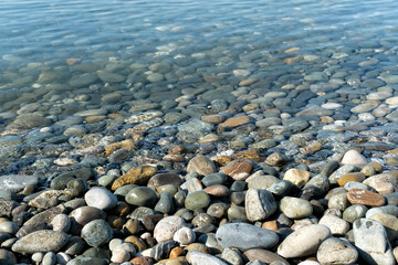 Clear water reveals smooth stones along the lakeshore on a sunny day in a tranquil natural setting